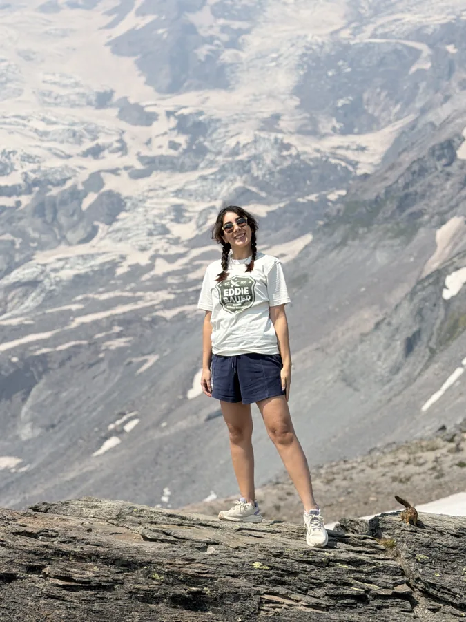 Maryam on a rocky outcrop with a glacier behind her.