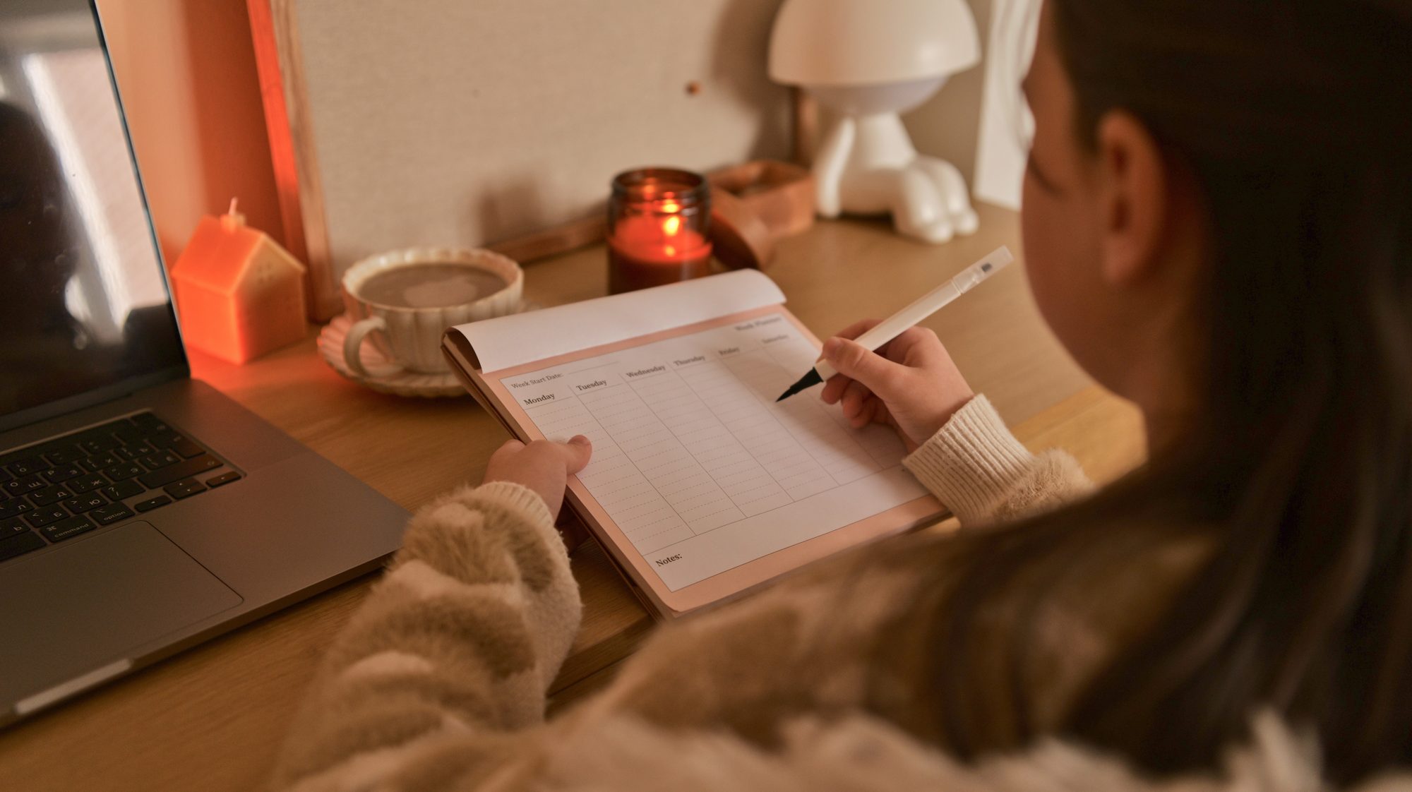 A student taking notes by lamplight beside a laptop