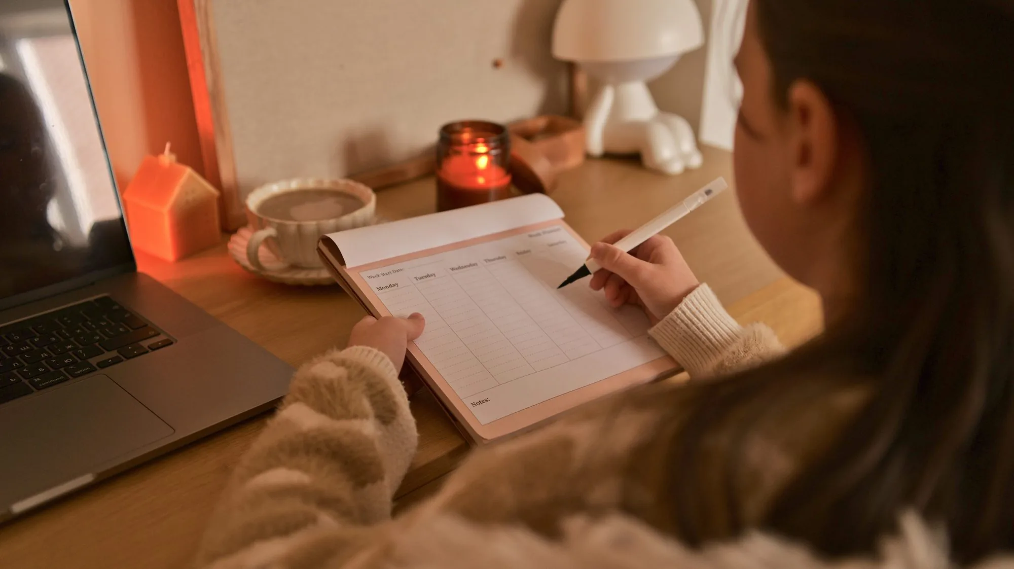 A student taking notes by lamplight beside a laptop